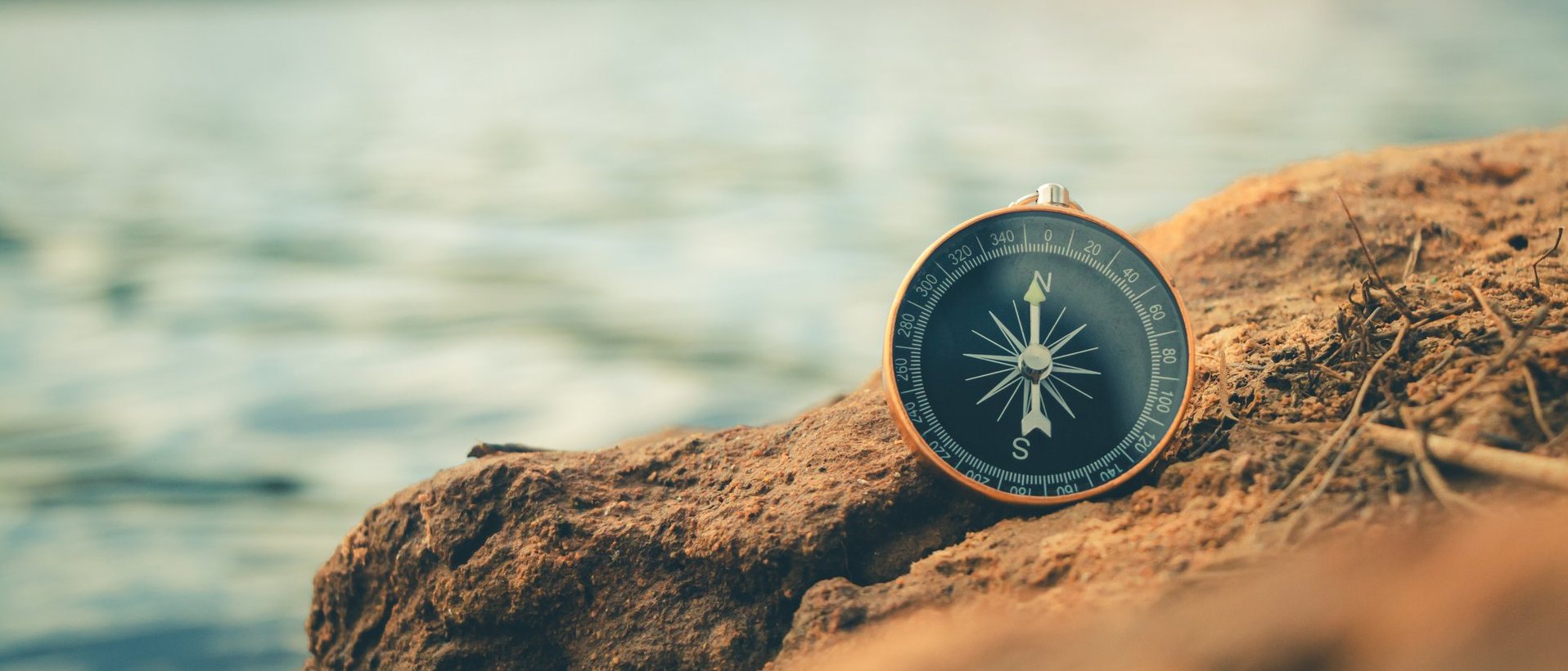 Kompass auf einem Felsen am Wasser als Symbol für Orientierung und Wegfindung