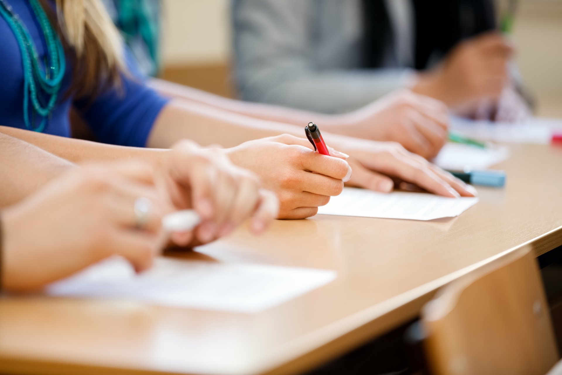 Schülerinnen und Schüler schreiben an Tischen im Unterricht.