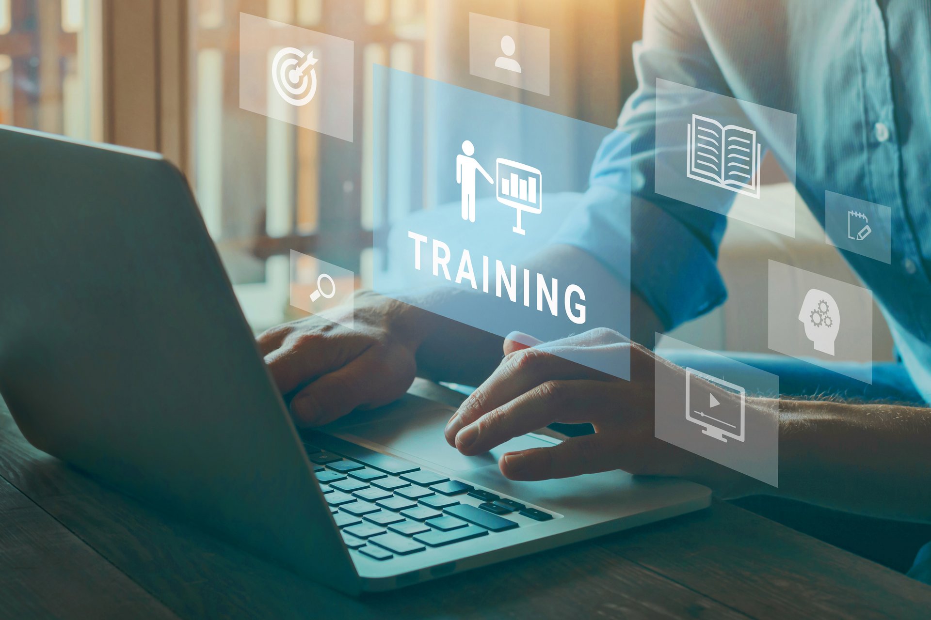 Person arbeitet am Laptop mit eingeblendeten Symbolen für digitale Schulungen und Weiterbildung